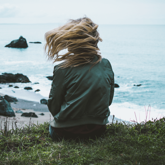 Девушка в раздумьях на скалистом утесе над морем